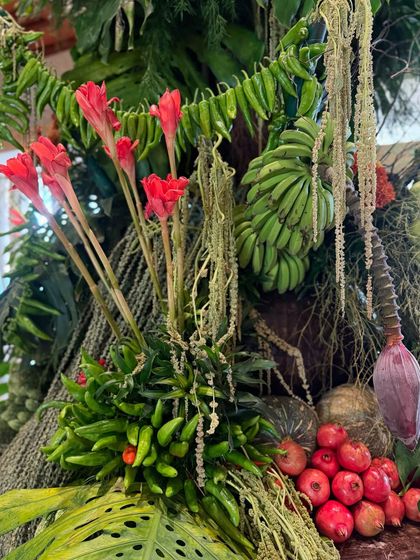 A close-up on the details: red torch ginger flowers rise above green chillies, raw bananas, and pomegranates. This is a reminder that beauty often lies in the most natural and unexpected combinations.