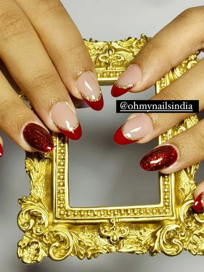 A classic festive look for the winter season. This design combines solid glittery red nails with elegant red French tips lined with a fine gold glitter accent.