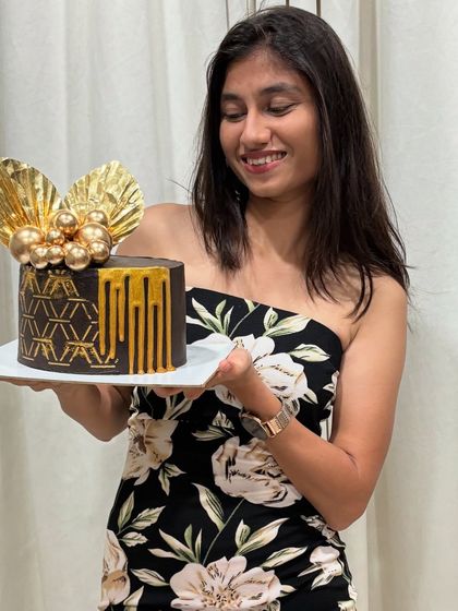 A photo of me with a birthday cake I made. This one is a rich chocolate cake with a modern geometric stencil design and golden drip.