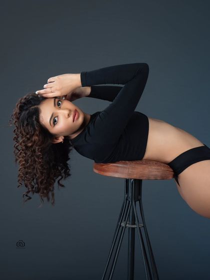 Using a simple prop like a stool, this studio portrait focuses on creating interesting lines and shapes with the body. The dark, neutral background ensures the model remains the sole subject of the image.