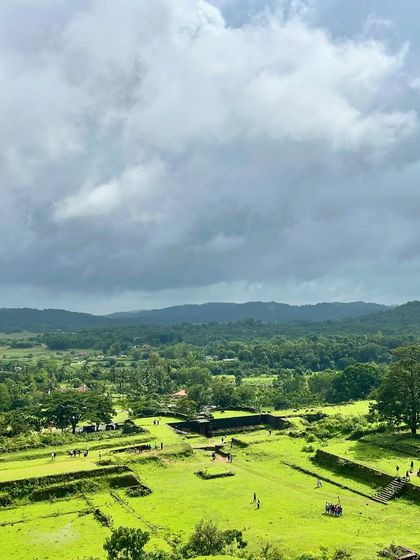 A panoramic view of the Nagara Fort ruins and the surrounding green landscape under a dramatic sky.