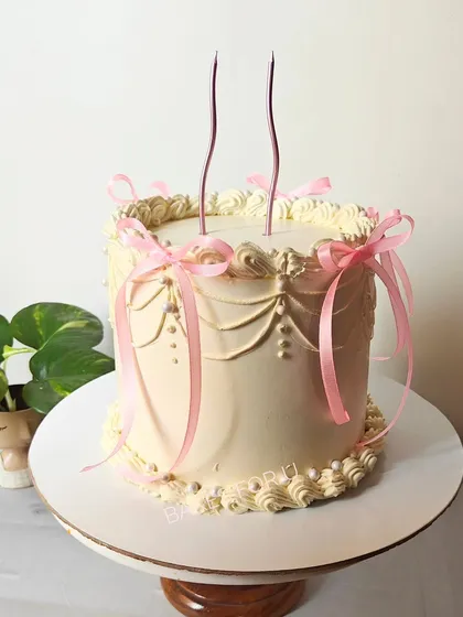 A classic vintage-style cake with delicate swag piping and pretty pink ribbon bows. This timeless design is perfect for birthdays, bridal showers, or any elegant occasion.