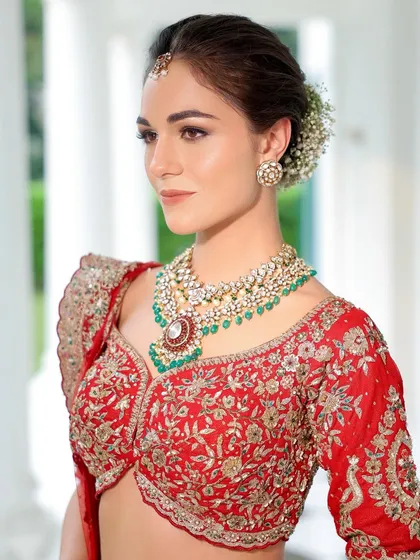 A classic portrait of our bride in red. The soft smokey eye and nude lip combination is a timeless choice that pairs perfectly with the ornate jewellery and red lehenga.