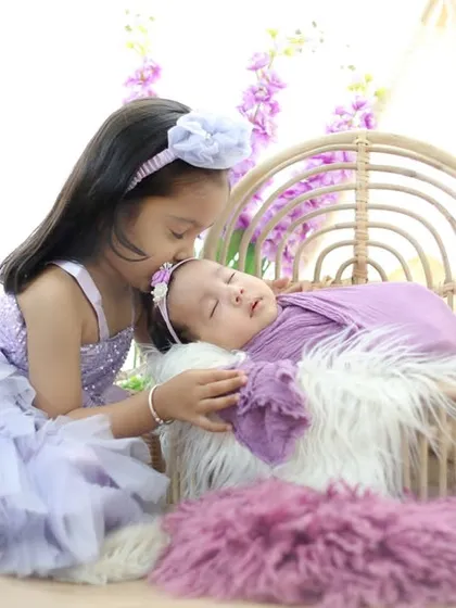 A big sister's gentle kiss for her new baby sibling is a moment of pure love. I specialize in creating a calm environment to capture these precious first interactions between siblings in a beautiful, coordinated setup.