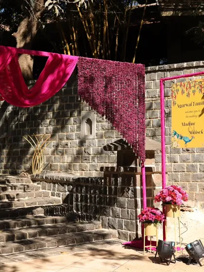 For this Mehendi entrance, we used a vibrant magenta floral curtain and drapery to create a pop of color against the rustic stone wall. A personalized welcome sign completes the look.