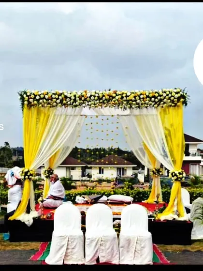 For outdoor ceremonies, I design beautiful mandaps that complement the natural surroundings. This setup uses bright yellow drapes and white floral arrangements to create a cheerful and elegant space for a daytime wedding.