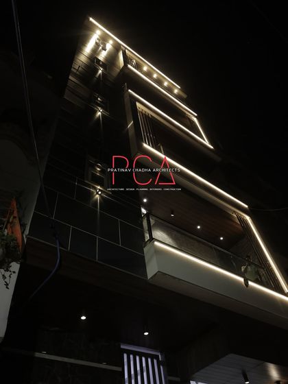 An upward-angle shot of 'The Cursive Abode' facade at night. The linear lighting traces the architectural frames, creating a sense of depth and luxury while accentuating the building's verticality.