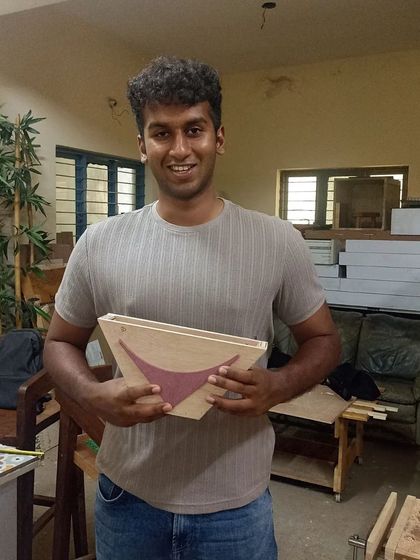 An interior design student with the stylish bowl he created, featuring an inlaid pattern of a different colored wood.