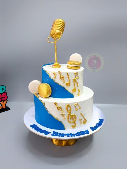 A two-tier musical-themed cake with a golden microphone, perfect for a music lover.
