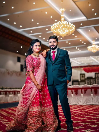 A lovely couple posing at their wedding reception. The simple yet elegant decor of the convention hall, with its beautiful lighting, provides a perfect backdrop.