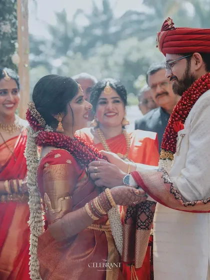 A candid moment during a traditional South Indian wedding ceremony. The decor is kept classic with beautiful floral garlands, allowing the couple's rituals to be the main focus.