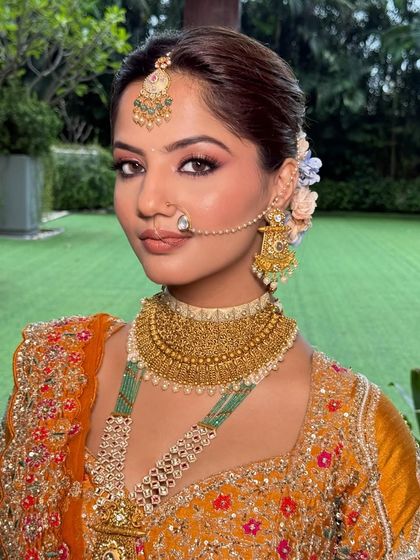 A stunning portrait. The makeup features a flawless base, defined eyes, and a soft lip, allowing the bride's natural beauty and her unique outfit to shine.