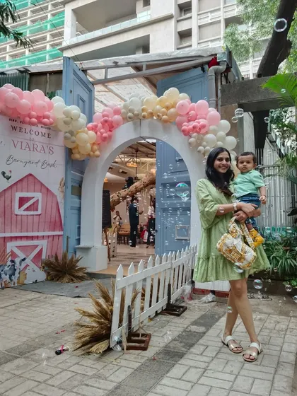 A barnyard-themed entrance for Viara's first birthday, featuring a custom 'Welcome' sign, a white picket fence, and a soft pastel balloon arch.