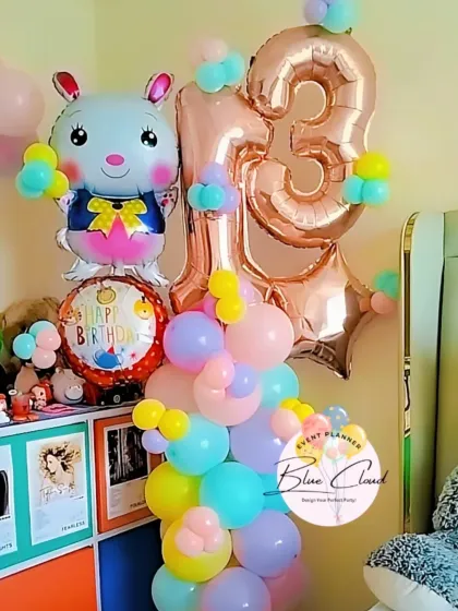 A cute balloon column for a 13th birthday, featuring a large rabbit foil balloon and pastel-colored latex balloons.