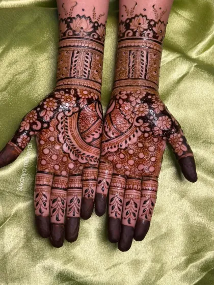 A beautiful siders mehendi design featuring dense floral work on the palms and lotus motifs on the fingers, creating a full and festive look.