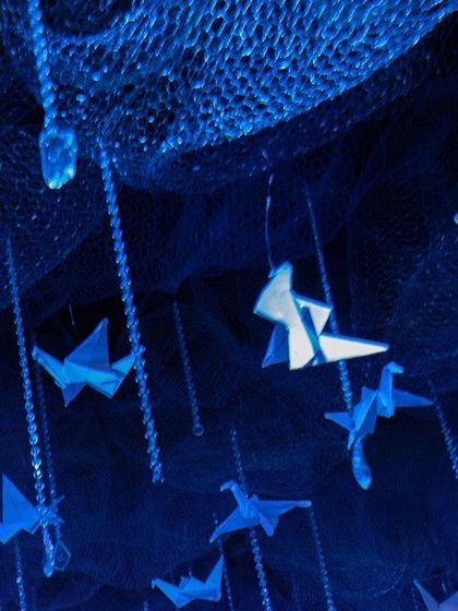 A macro shot focusing on the delicate paper birds and sparkling crystal strings that made up the magical ceiling canopy for the winter-themed event.