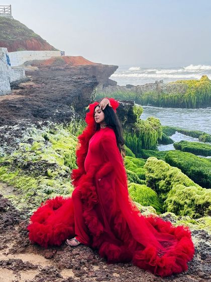 The vibrant red of this ruffled gown creates a stunning contrast against the rocky, moss-covered shoreline. This is a perfect example of how my gowns can be used for dramatic, on-location maternity photography.