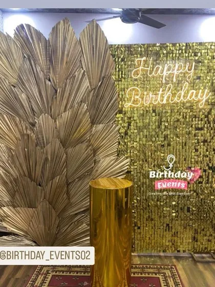 Your sangeet or cocktail party needs a glam corner. This photo booth setup features a shimmering gold sequin wall, a custom "Happy Birthday" neon sign, and elegant dried palm leaves for a super trendy look. We can customize the neon sign for your event.