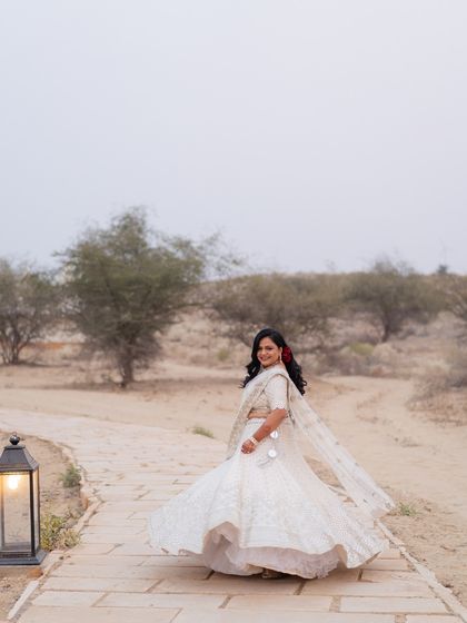 The bride twirling in her all-ivory lehenga, a pop of red from the rose in her hair adding a touch of romance.