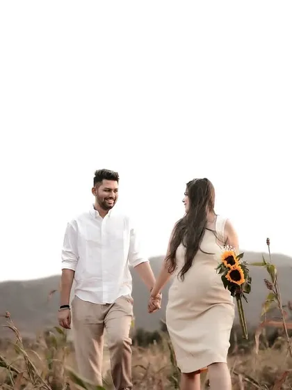 A wide shot of the couple walking through a golden field, with the mountains in the distance. The expansive view and warm light create a sense of a grand, beautiful adventure.