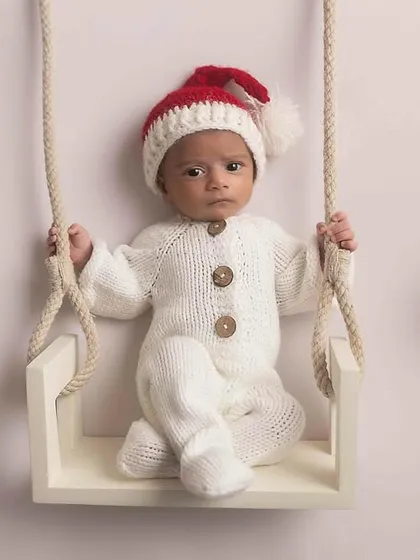 Our little Christmas baby sitting on a swing, surrounded by festive golden ornaments.