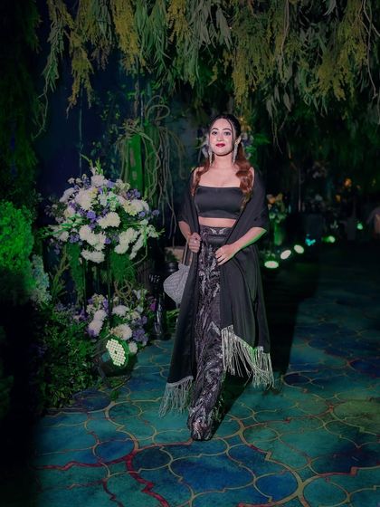 Walking through the beautifully decorated venue in my Sangeet outfit. The dark outfit contrasted beautifully with the lush green and floral decor.