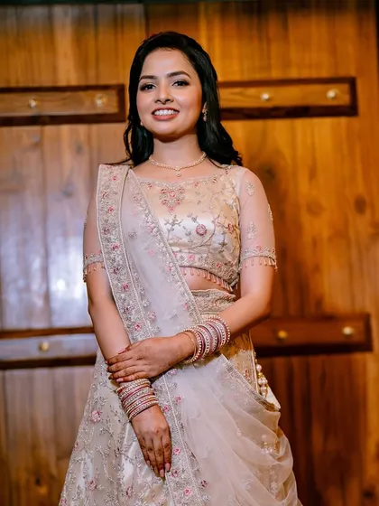 A classic portrait against a wooden backdrop. The warmth of the wood complements her skin tone and the soft colors of her lehenga.