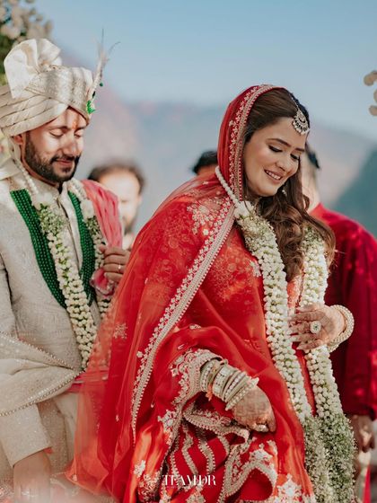 The bride's entry at her Rishikesh wedding. Her soft makeup and flowing red lehenga create a stunning visual as she walks towards her new beginning.