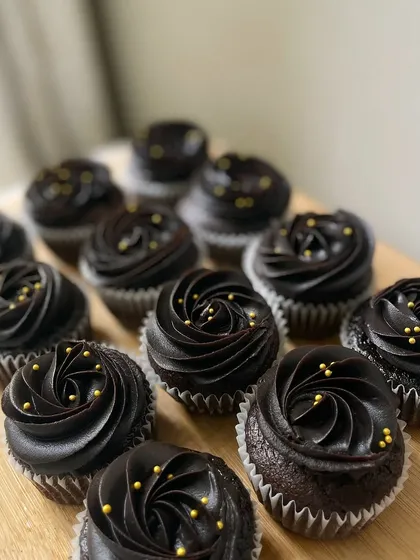 A batch of our elegant chocolate cupcakes, topped with rich chocolate frosting and delicate gold sprinkles. These were packed as return favors for a little one's birthday.