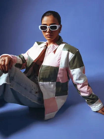 This shot highlights a unique patchwork leather jacket. The simple, seated pose and the clean background ensure the colorful jacket is the main focus.