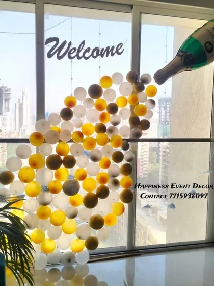For a fun and unique welcome decoration, I created this design of a champagne bottle pouring out bubbles. The balloons are arranged against a large window, using the city view as a backdrop.