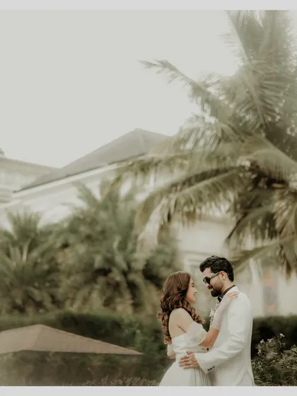 A classic, romantic portrait set against the lush greenery of the wedding venue. The couple's gentle embrace and gaze towards each other create a timeless image of love and togetherness.