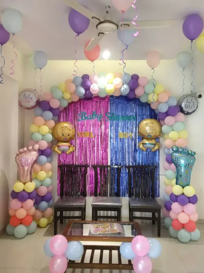 A pastel-themed baby shower decoration. The soft, multi-colored balloon arch and 'Baby Shower' backdrop create a gentle and celebratory setting.