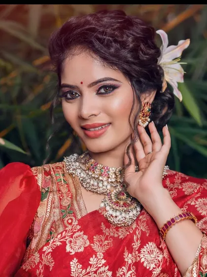 A model in a red brocade saree, wearing a statement polki and kundan style necklace, perfect for a wedding guest.