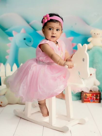 A whimsical pastel wonderland. This little girl in a pink dress rides a rocking horse in a dreamy landscape of soft colors and cute characters.