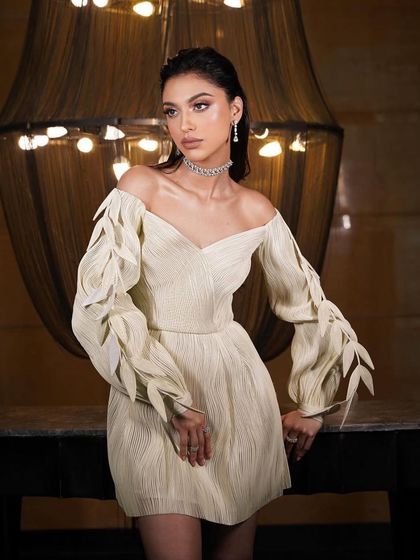 A full-length view of the unique leaf-detailed dress, showing how the soft makeup complements the artistic design.