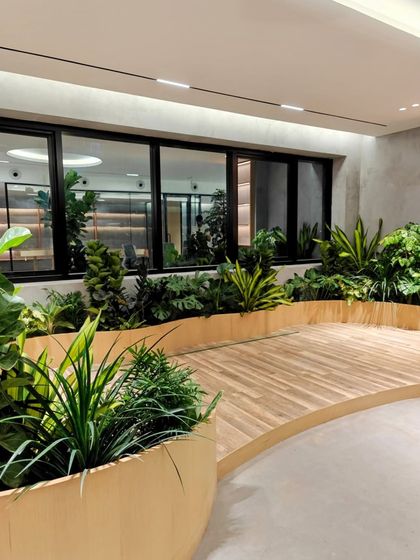 Another view of the biophilic office in Hyderabad. The curved wooden deck and integrated planters create a natural, flowing breakout area for employees to relax and recharge.