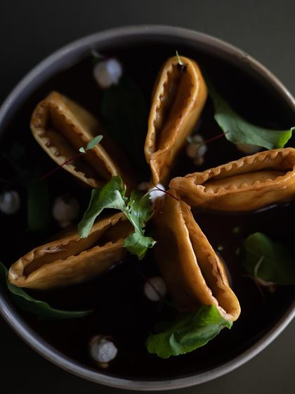 The beautiful star-like presentation of our Slow Cooked Lamb and Truffled Potato Doppio Agnolotti, floating in a dark, savory lamb jus.