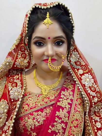 A portrait of a classic North Indian bride. The makeup is timeless, with defined eyes and a soft red lip that perfectly matches the traditional attire.