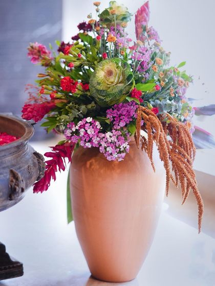 A colorful floral arrangement in a terracotta pot, part of the vibrant decor for a traditional Pellikuthuru ceremony.