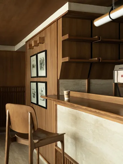 A detail of the coffee bar, where a single stool invites a moment of interaction with the barista. The material palette is restrained and tactile.