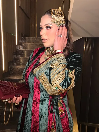 A side profile of the royal beauty, showcasing the intricate passajewelry and the glamorous eye makeup.