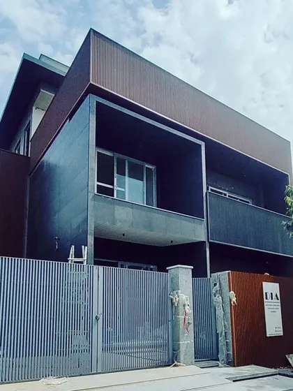 A nearly completed project in Noida showcasing a bold, minimalist aesthetic. The design is characterized by its clean, boxy forms, a dark color palette, and the use of a prominent fluted facade, which adds texture and a modern edge to the building.