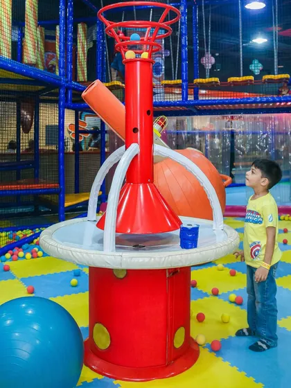 A young boy watches in fascination as the ball volcano erupts, sending a shower of soft balls into the air. This feature combines science and fun.
