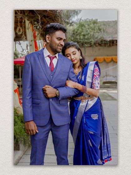 A classic portrait of the newly married couple, the groom in a sharp blue suit complementing the bride's saree.