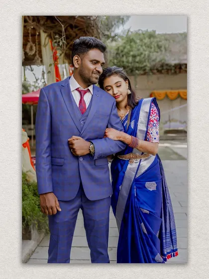 A classic portrait of the newly married couple, the groom in a sharp blue suit complementing the bride's saree.