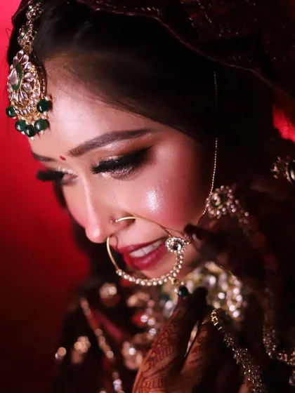 A close-up bridal portrait under dramatic lighting. The smokey eye and perfectly defined features create a look of timeless elegance.