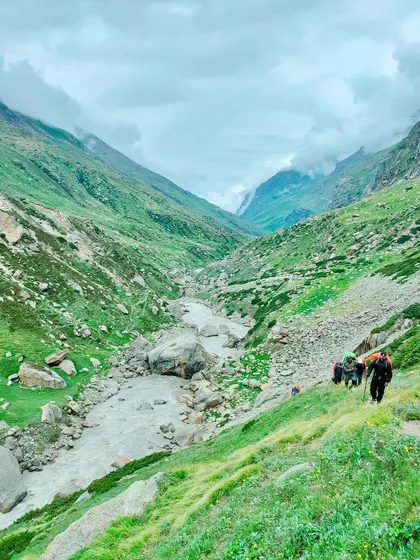 Trekkers descending into the valley on the Pin Parvati trail, with the river carving its way through the landscape.