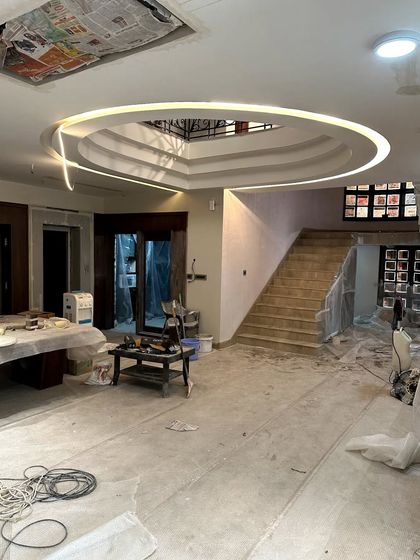 Embracing the beauty of progress. Here, a living space is mid-construction, with the intricate ceiling design and lighting already installed while the floors and walls await their final finish.