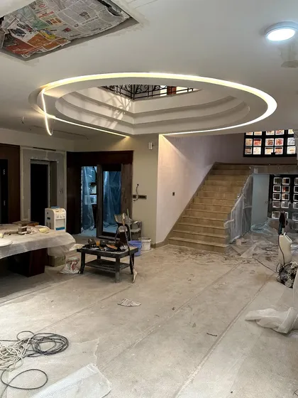 The beauty of progress. This image captures a living space mid construction, with the ceiling's complex lighting design installed but the floors and walls still raw.